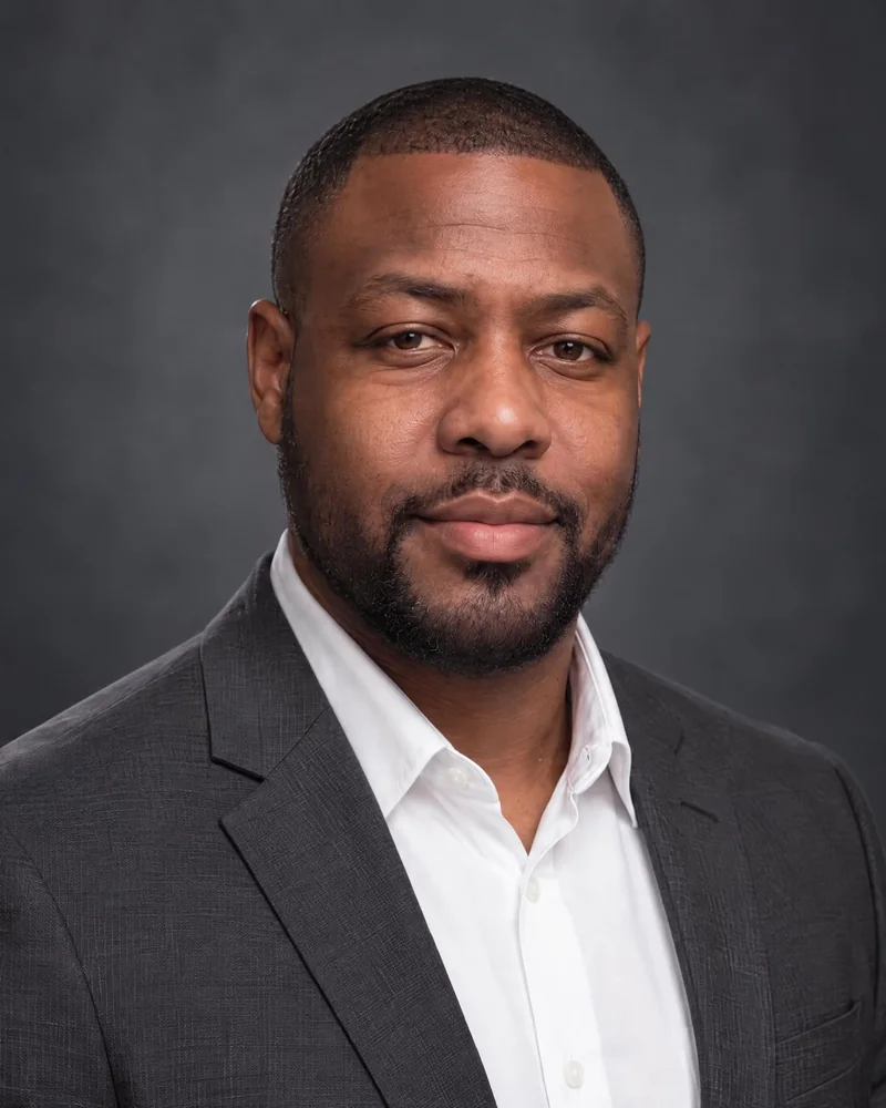 Jobfoto headshot: lawyer in a charcoal suit and white shirt on a dark gray backdrop
